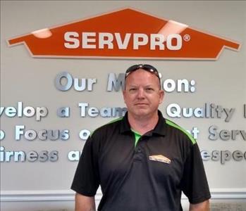Man standing in front of SERVPRO logo with green and black polo shirt