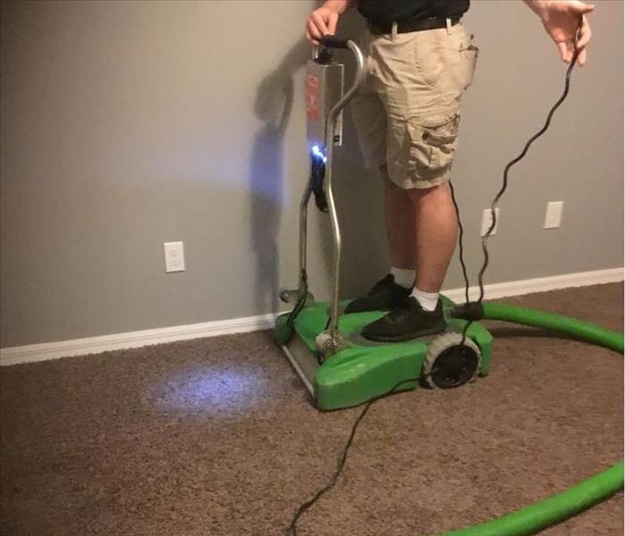 Man standing on Extractor machine and extracting water from carpet