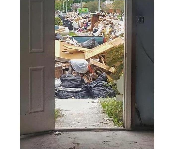 A front door of a home opened looking out to piles of debris