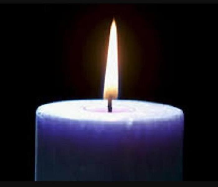 Purple candle with flame on black background