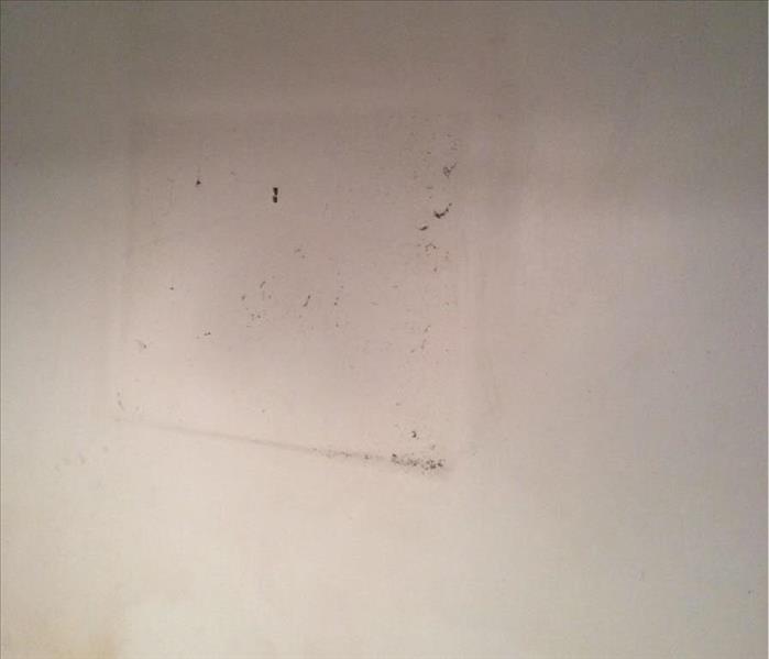 Wall with an outline of soot around where a picture hung from a fire damage.  