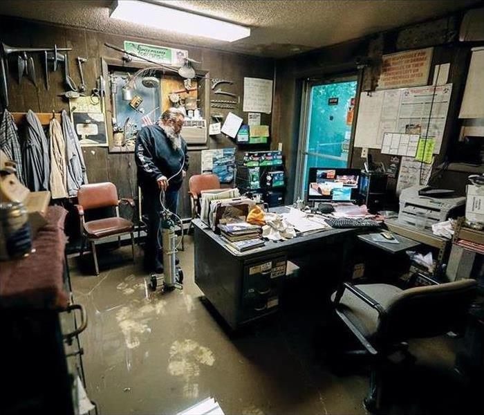 Man standing in water in his office with a desk full of paperwork